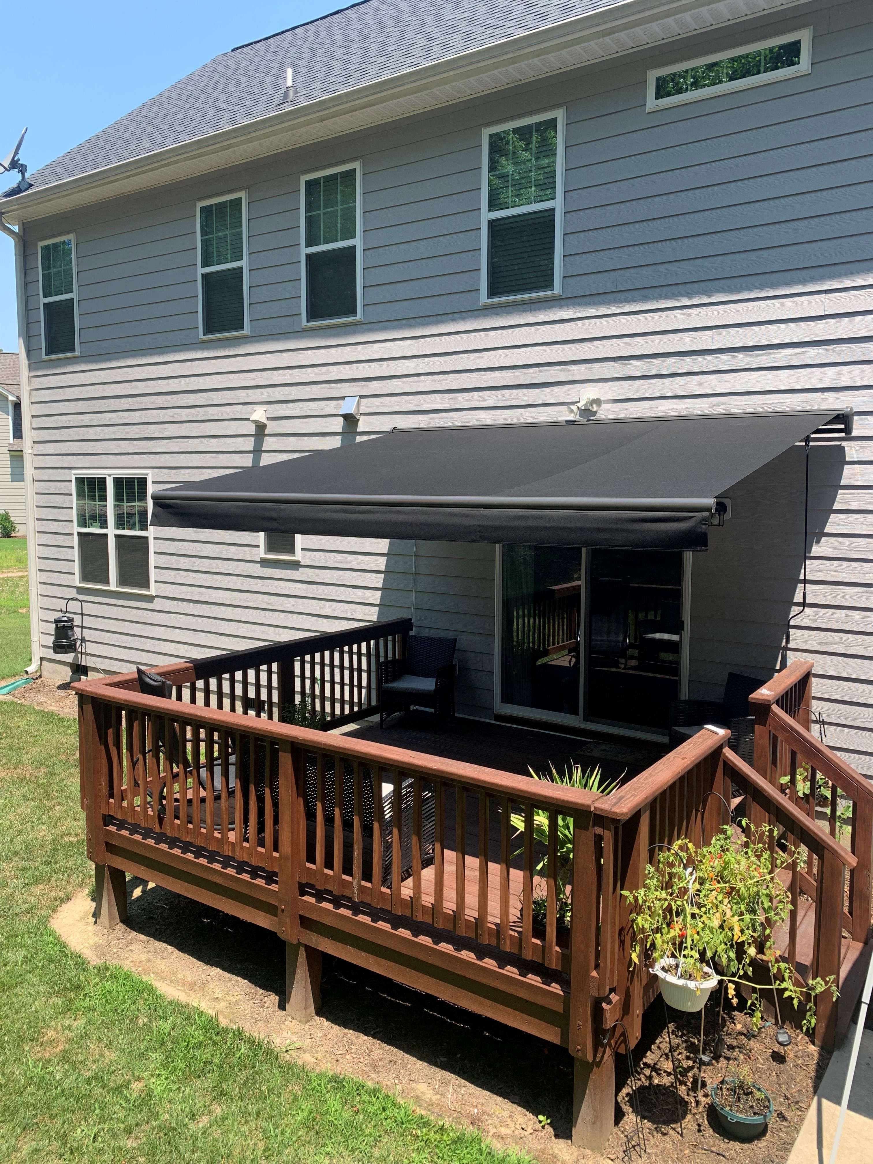 Charcoal motorized awning on a wood deck