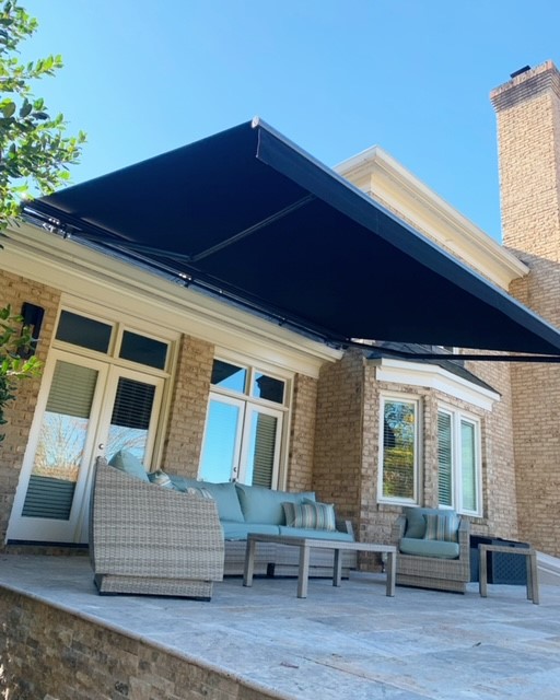 Large navy retractable awning over a luxury outdoor sofa set